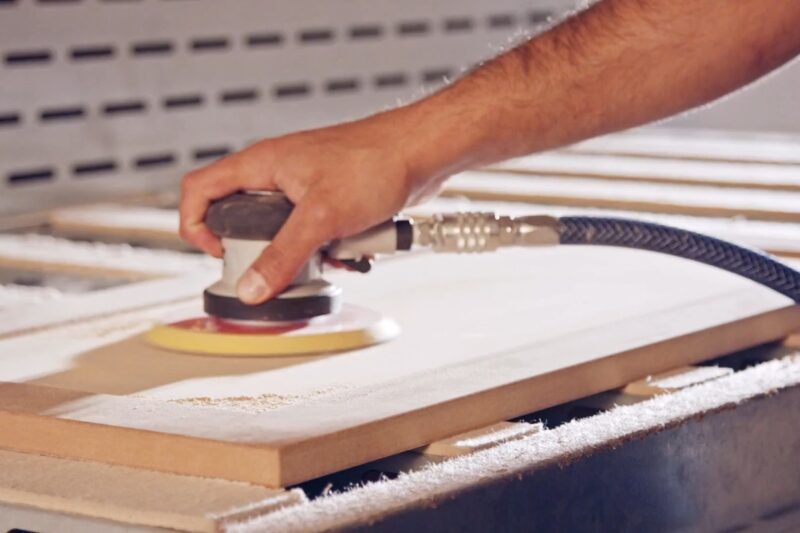 osoba brusi drvenu površinu