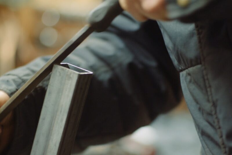 osoba brusi metalnu nožicu za stolicu