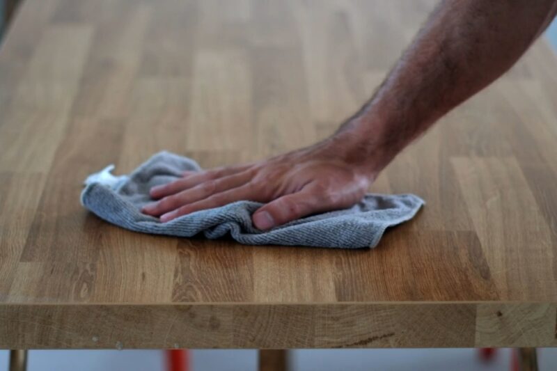 osoba briše drveni nameštaj