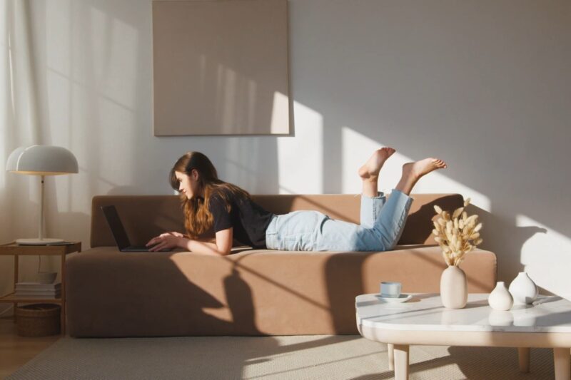 prikaz devojke koja leži na braon ugaonoj, stolčića i lampe